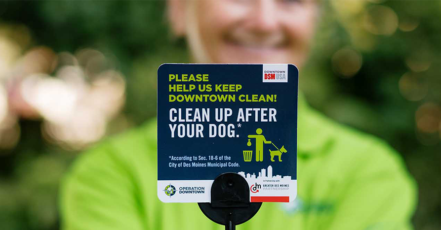 Close up of a sign that says, "Please help up keep downtown clean! Clean up after your dog."